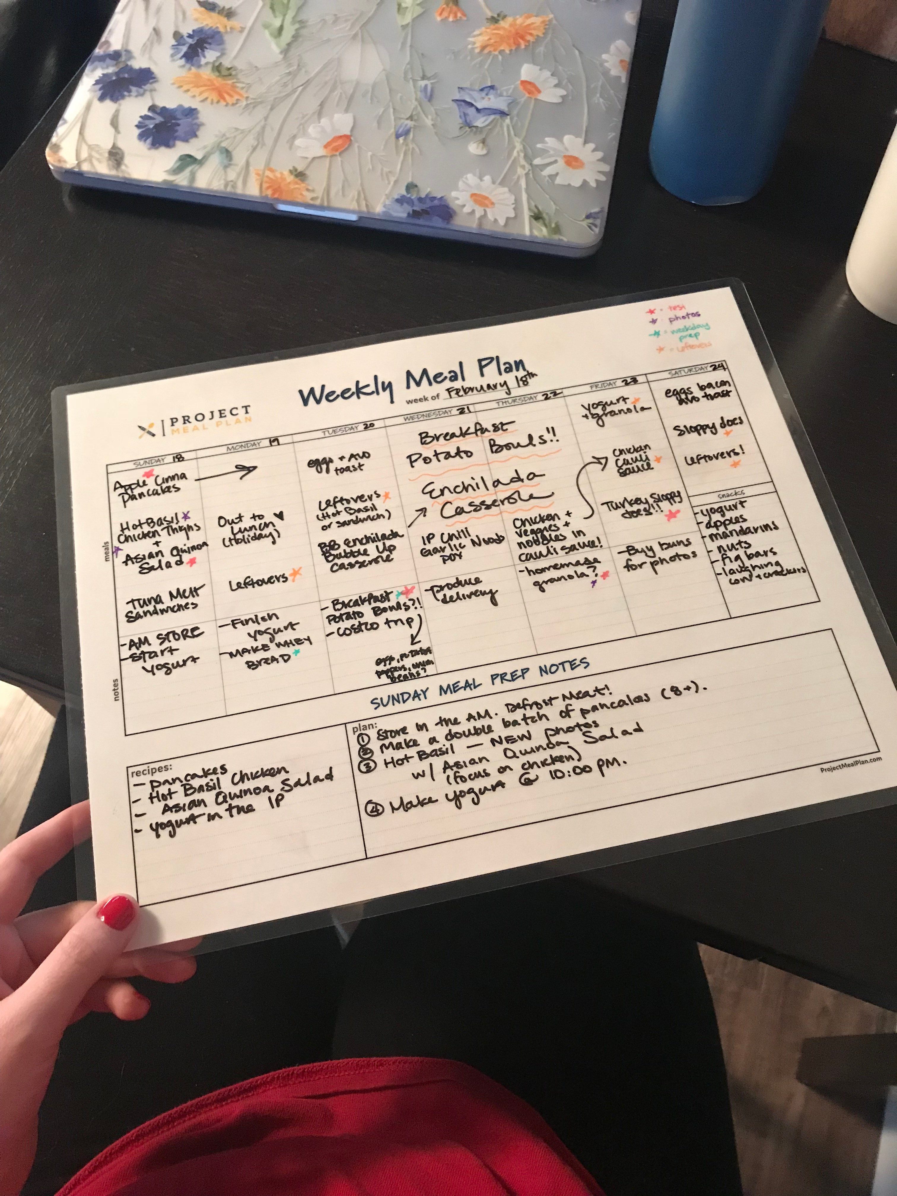 A laminated chart with a handwritten meal plan showing breakfast lunch and dinner for the week of February 18th.