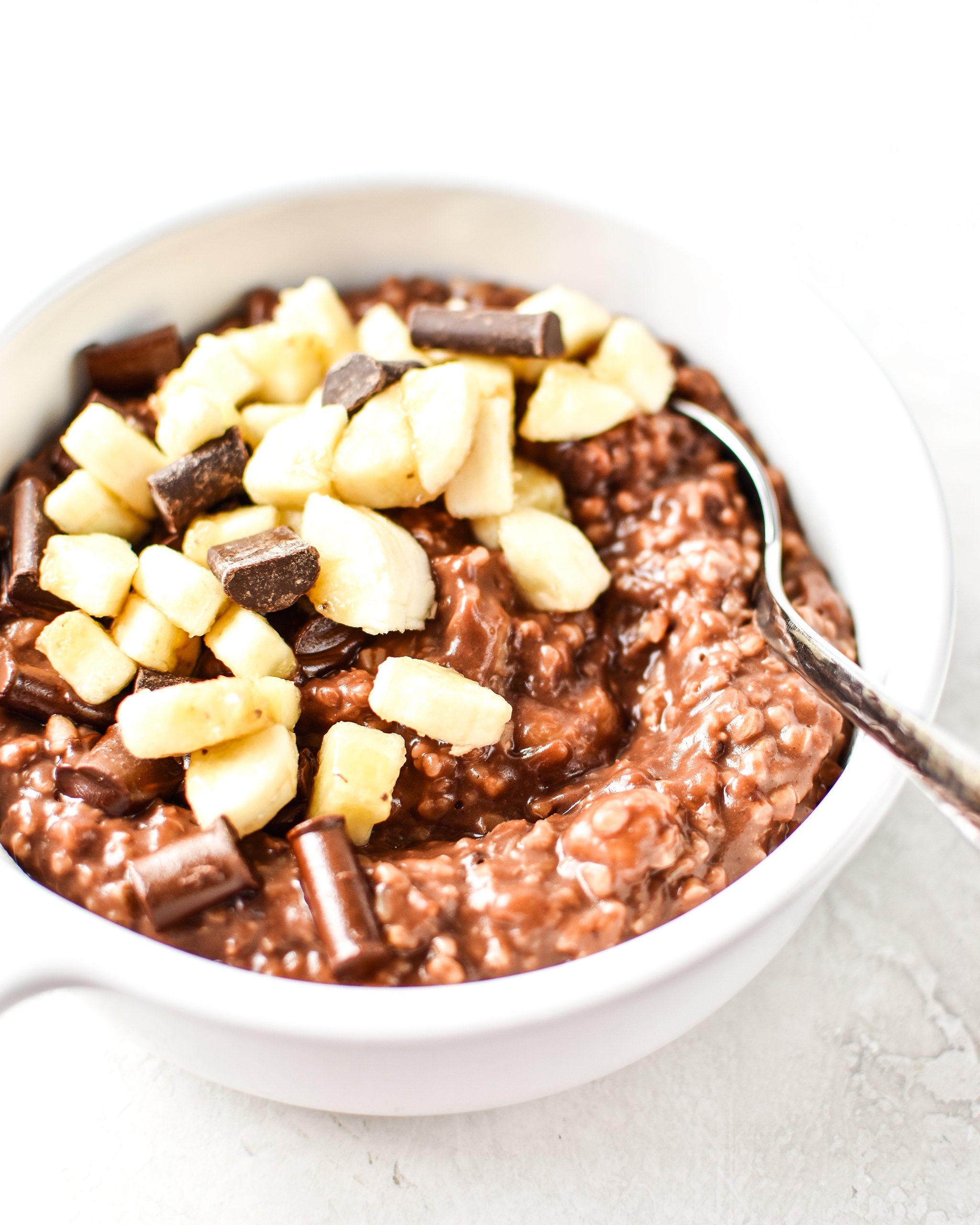 a bowl of chocolate banana steel cut oats made on the stovetop, topped with banana and chocolate chunks