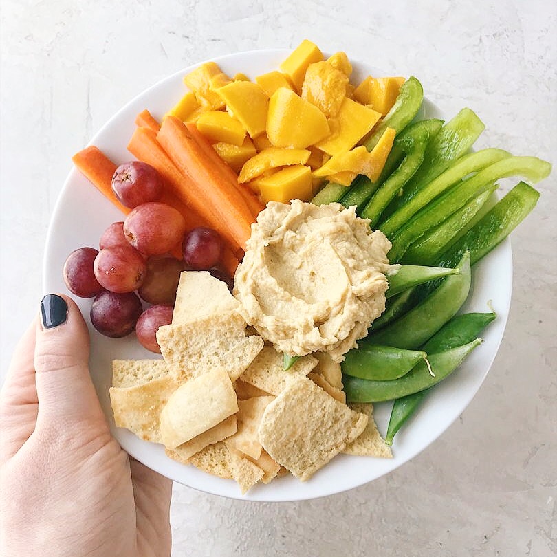 A simple no-heat lunch with grapes, pita chips, hummus, mango, snap peas, bell pepper and carrots.