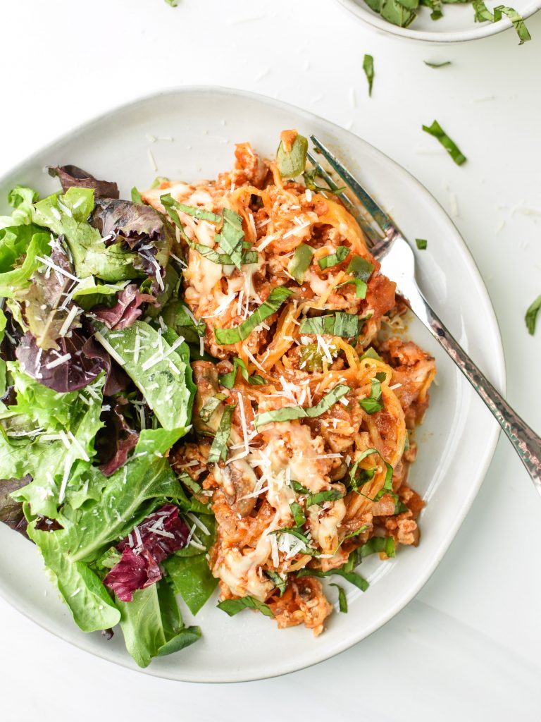 A plate with spaghetti squash spaghetti bake and a side salad with fork.