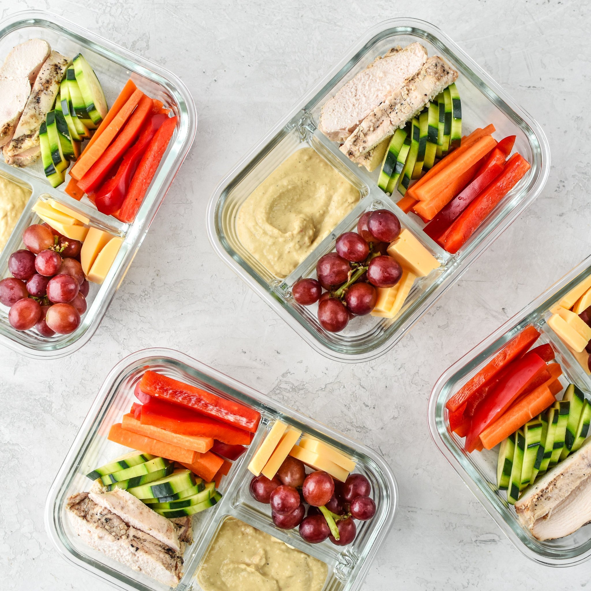 Chicken & hummus place meal prep in 3 compartment containers.