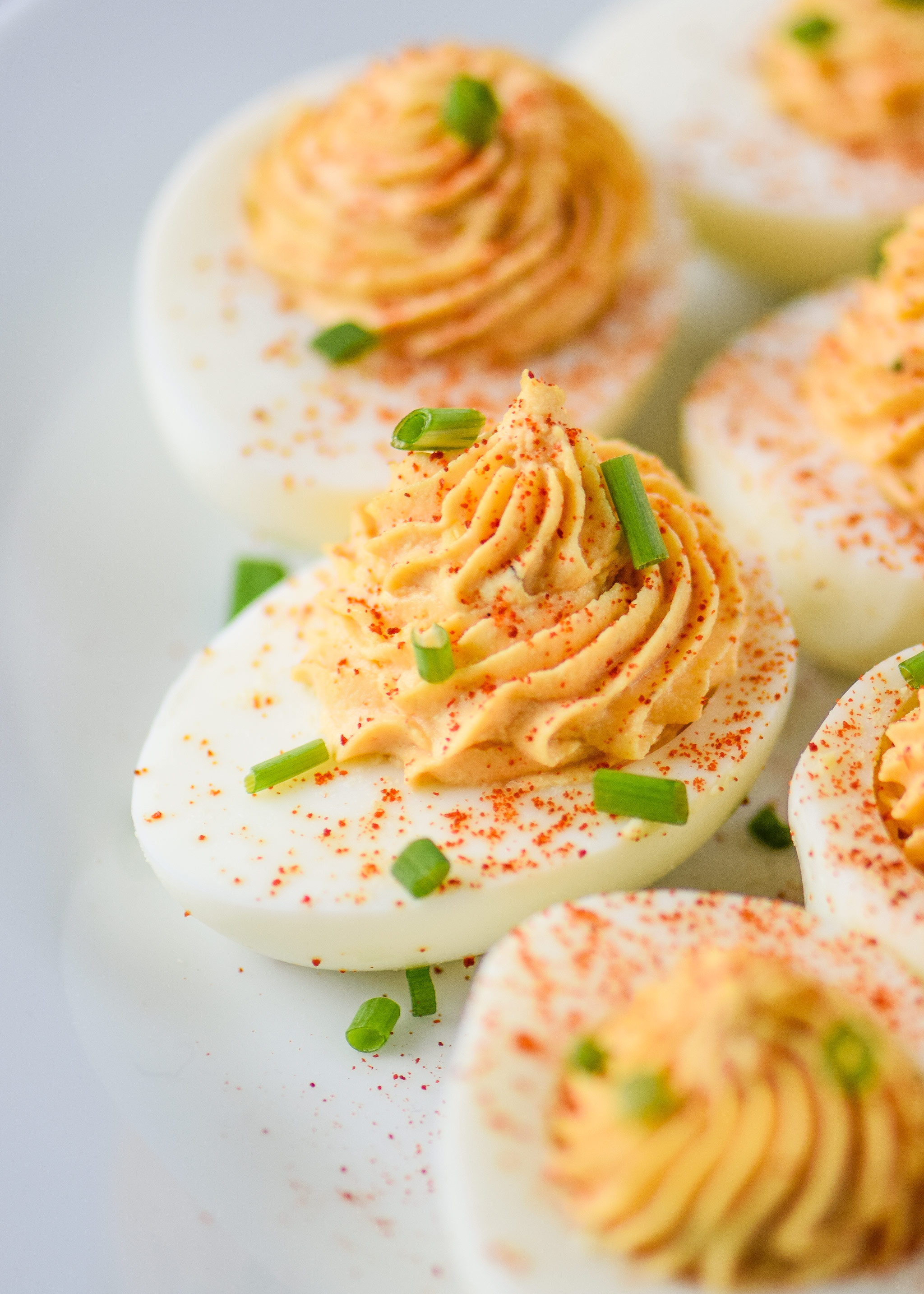 Whole30 Buffalo Deviled Eggs pictured with green onions and smoked paprika on top.