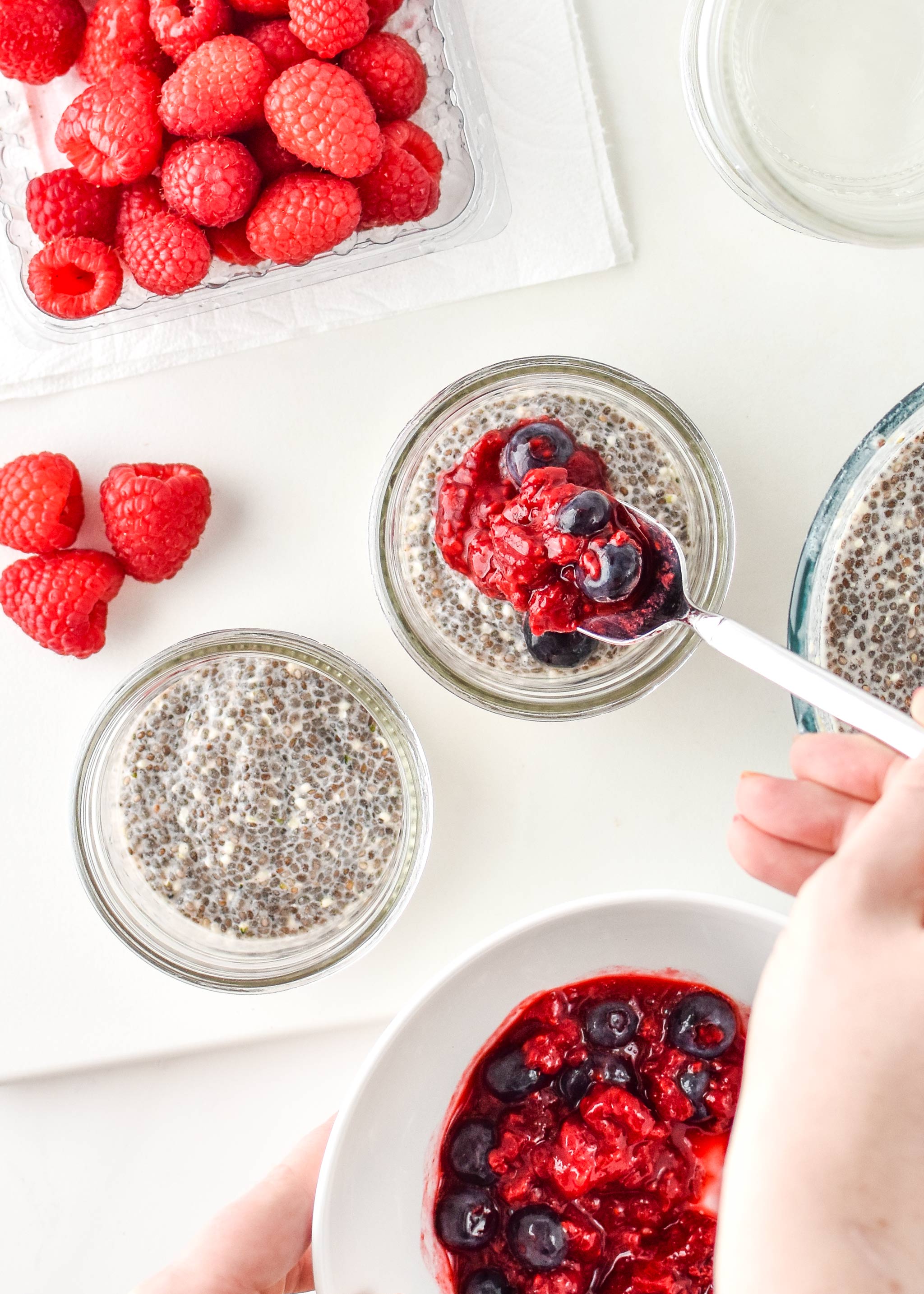 Adding mashed berries to create the chia pudding breakfast parfaits 
