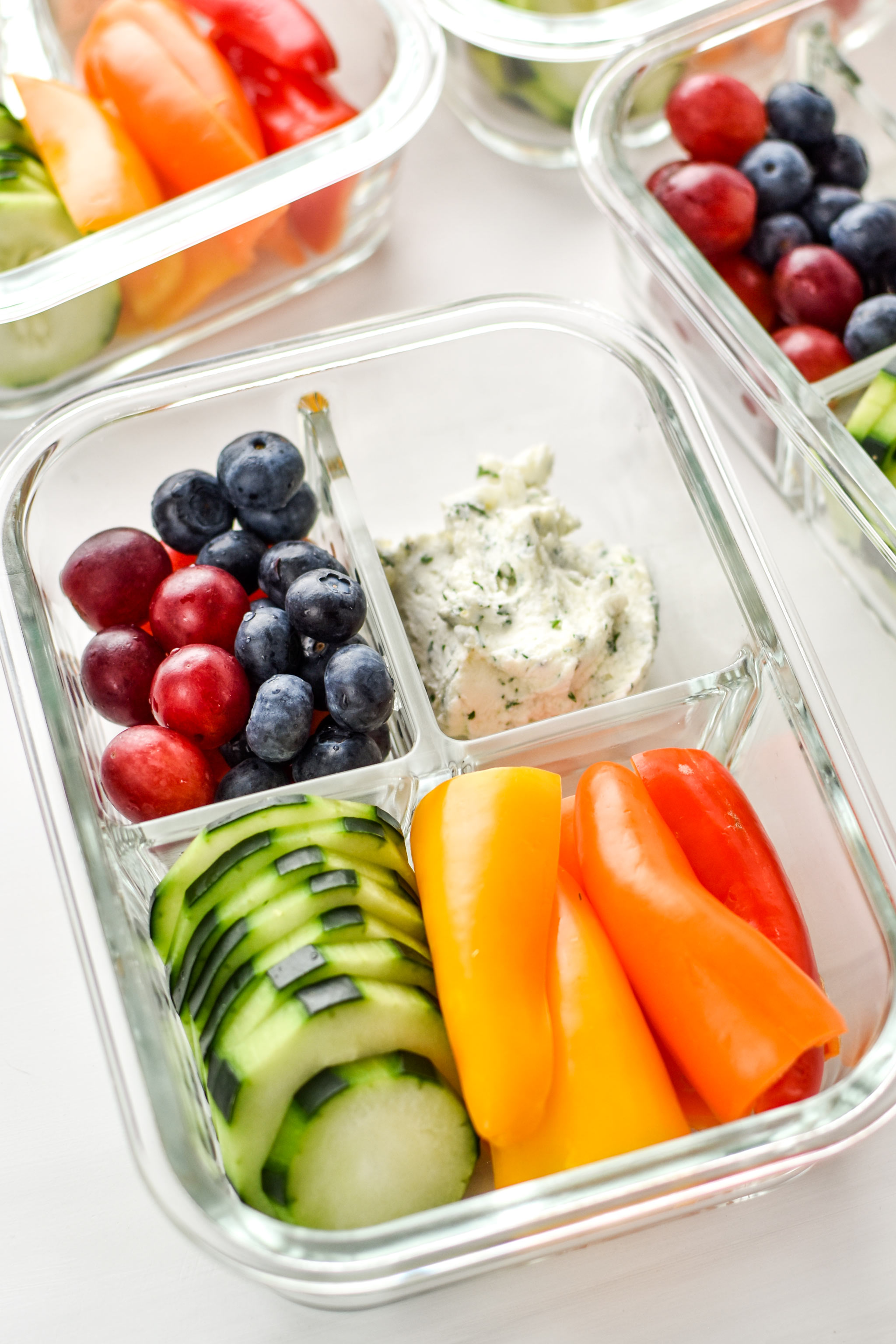 An herbed goat cheese rainbow snack box with fruits and veggies.