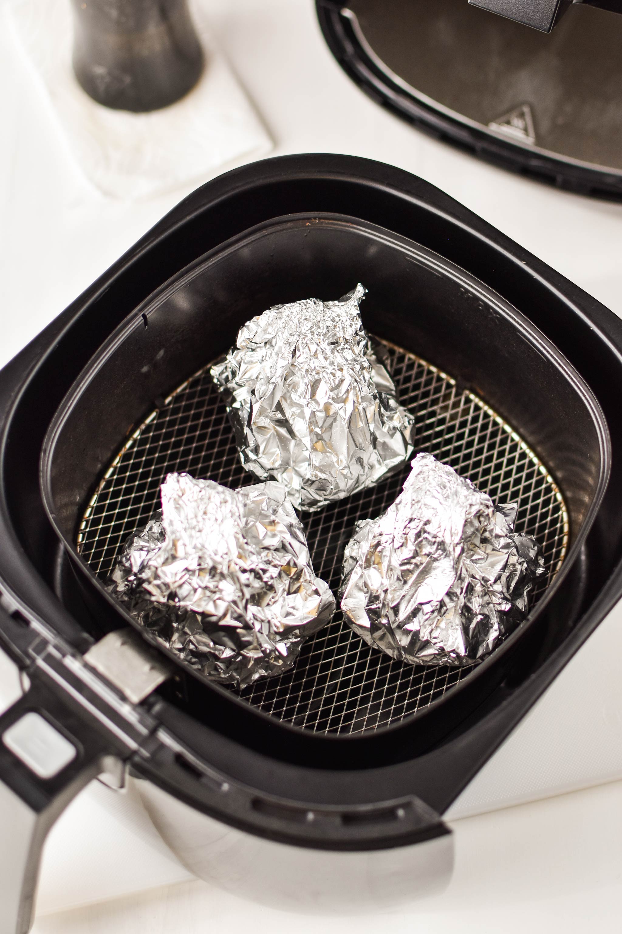 Prepared garlic heads are in the air fryer to be roasted