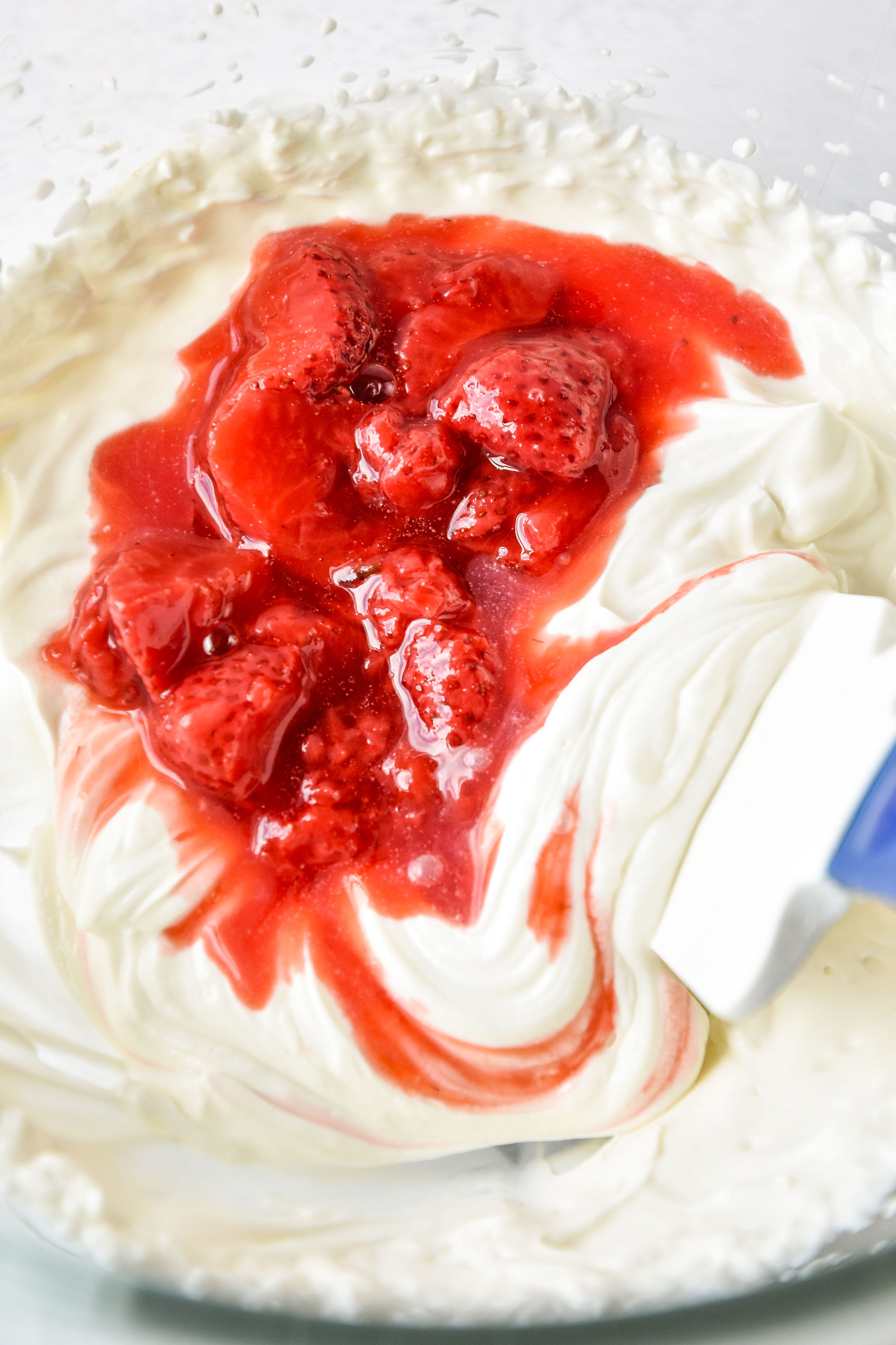 adding strawberry sauce to the whipped greek yogurt