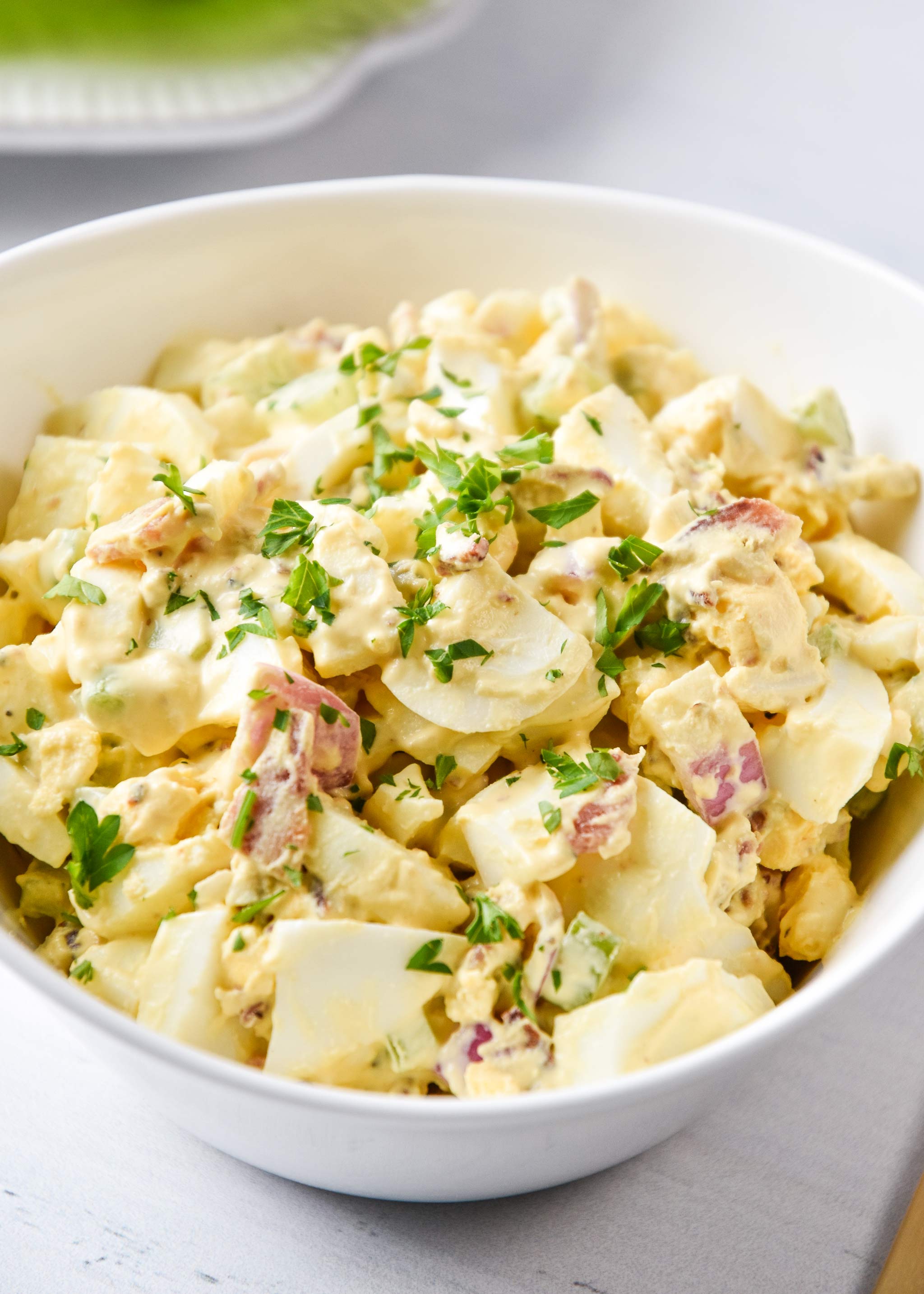 egg salad with bacon in a bowl with parsley on top