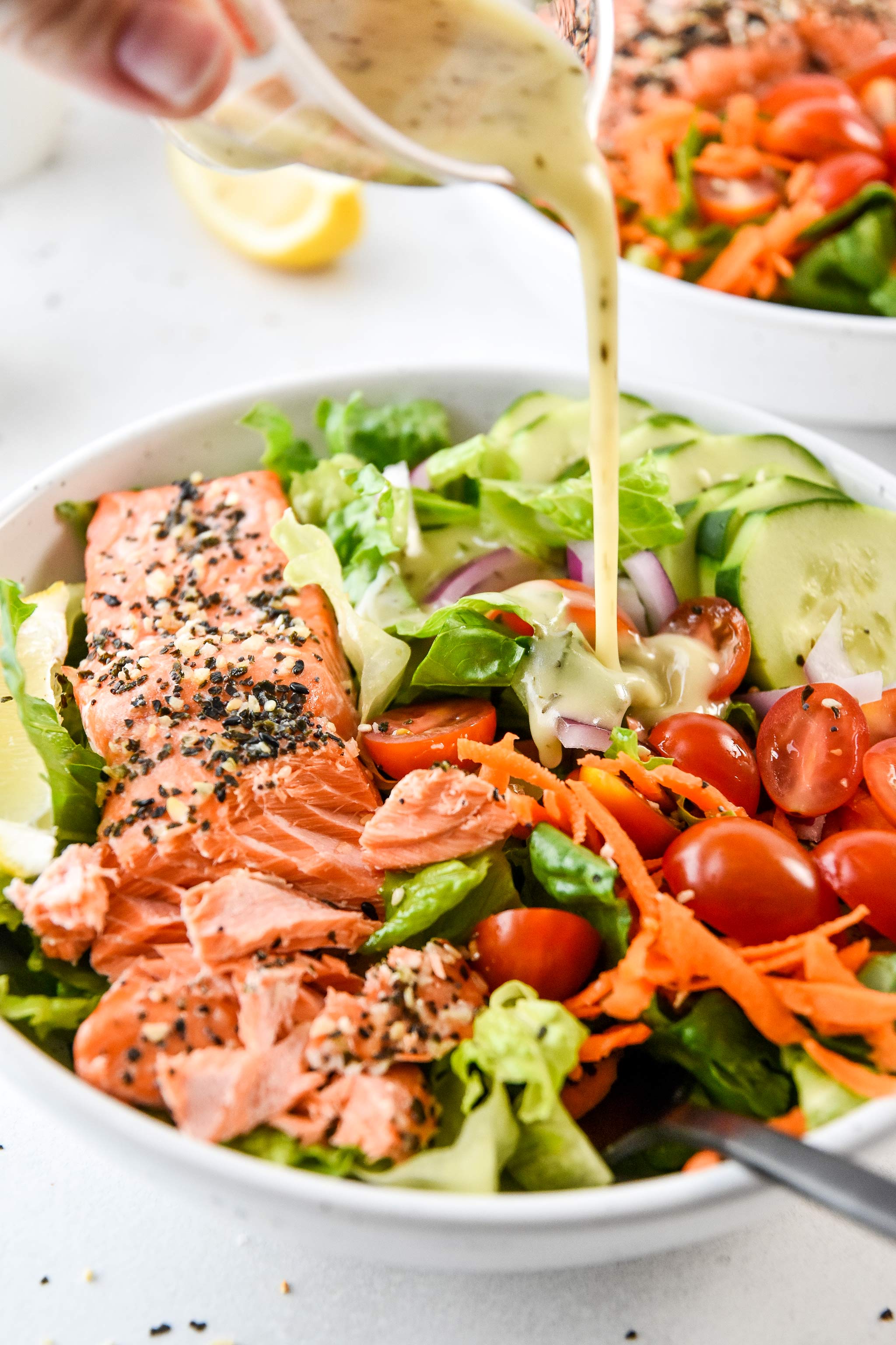 adding dressing to the everything bagel baked salmon salad