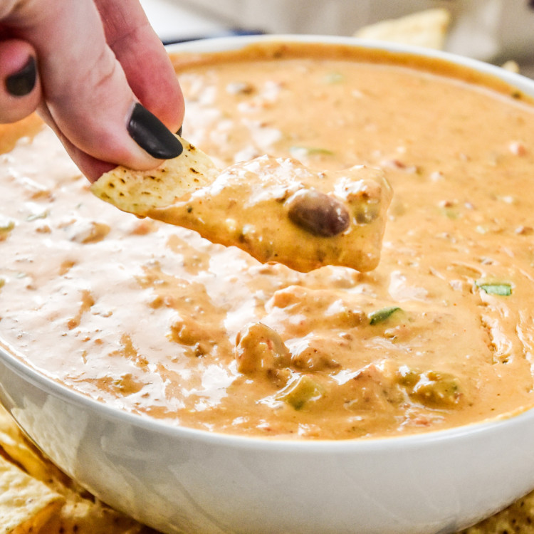 dipping a chip into the chili cheese dip