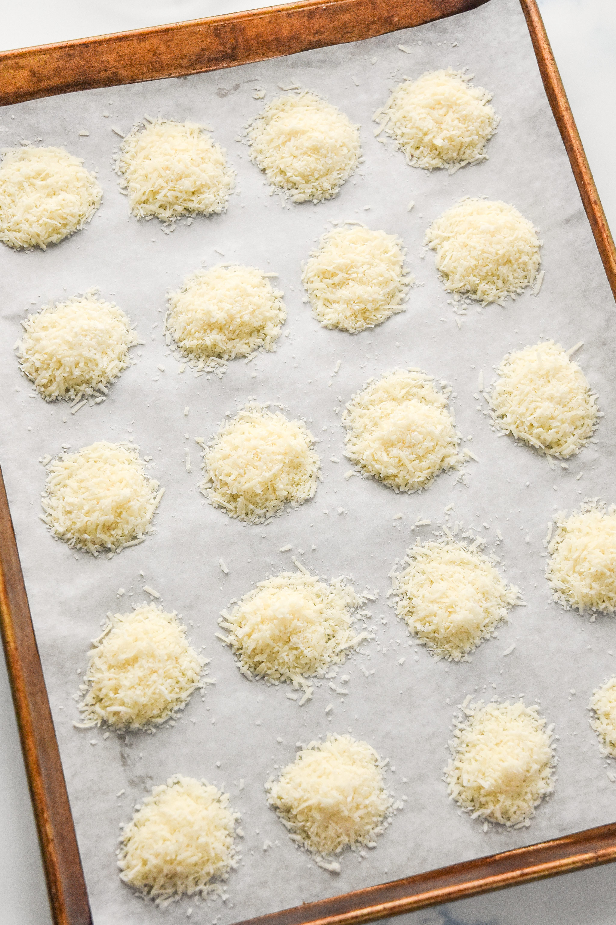 parmesan cheese piles on a baking sheet