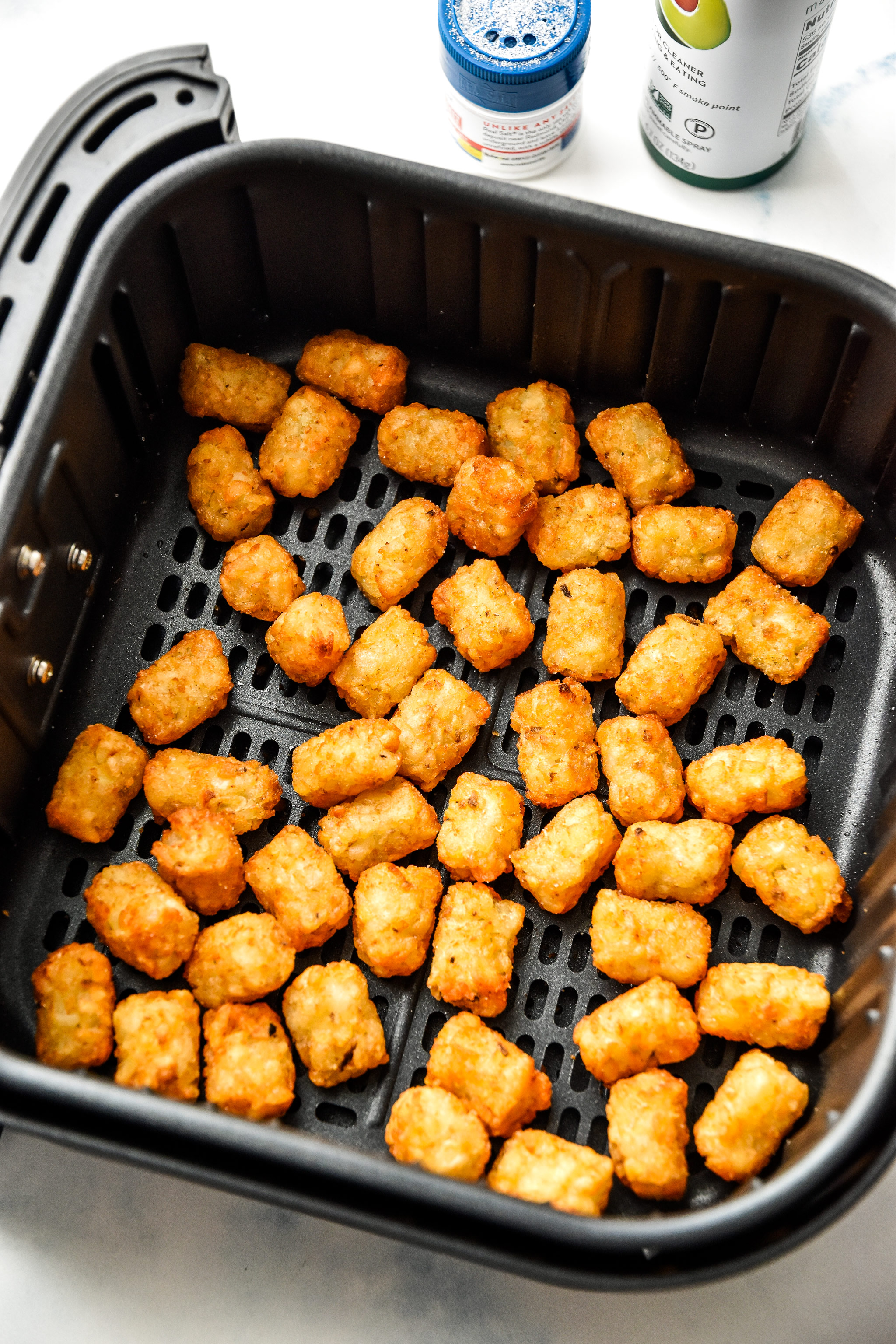 frozen tater tots cooking in an air fryer