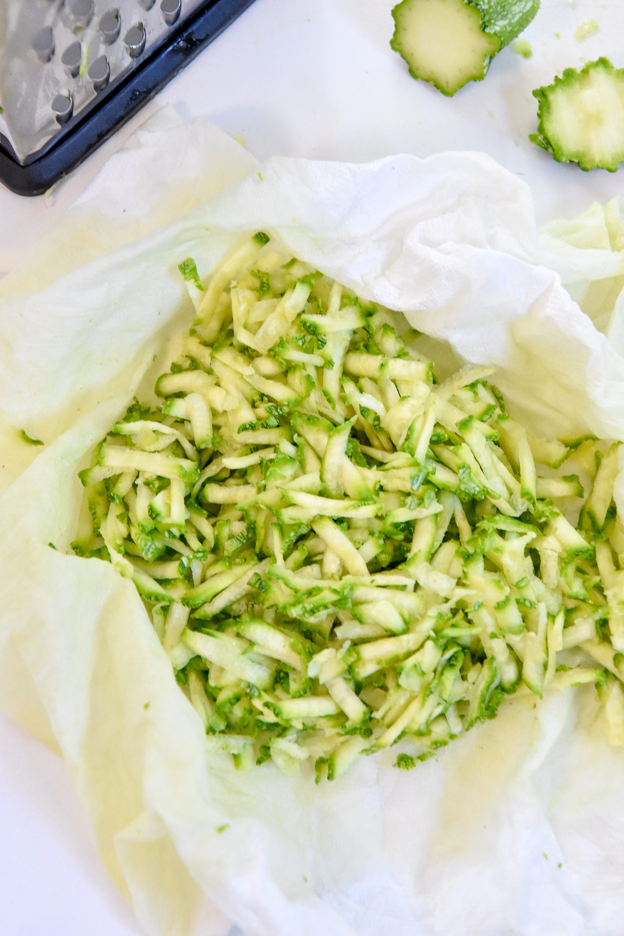 shredded zucchini in a paper towel being prepared for the muffins.