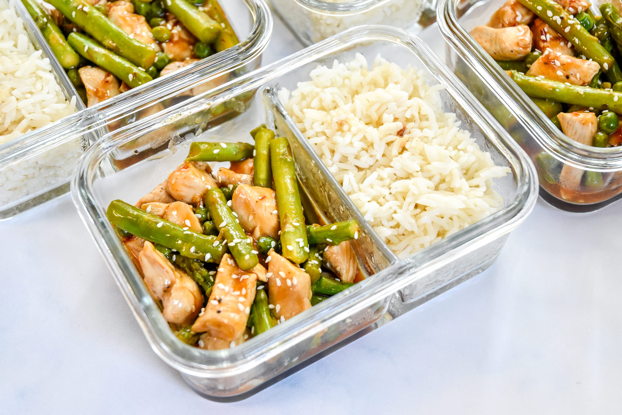 meal prep spicy chicken and asparagus in glass meal prep containers