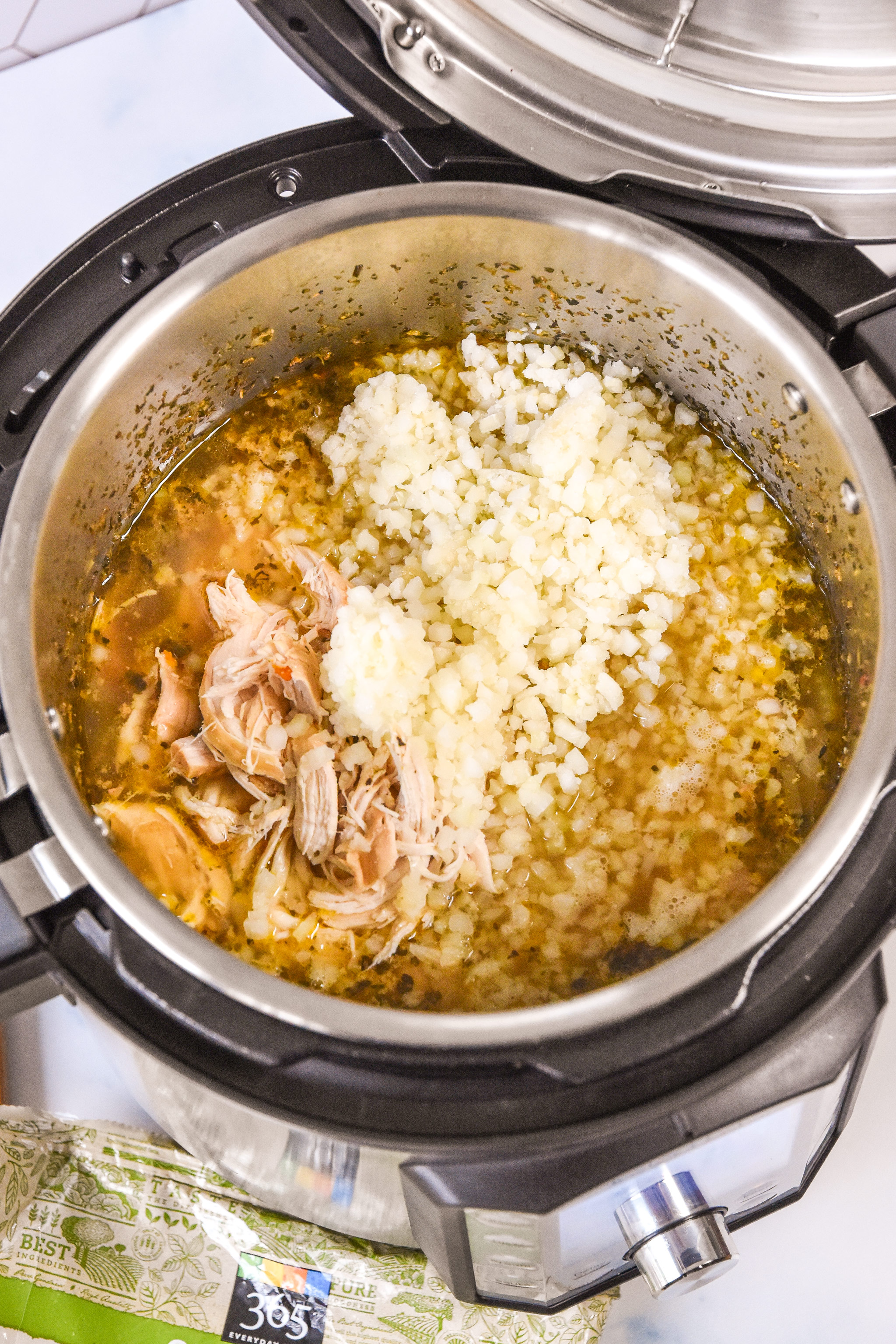 adding cauliflower rice and shredded chicken to the pot.