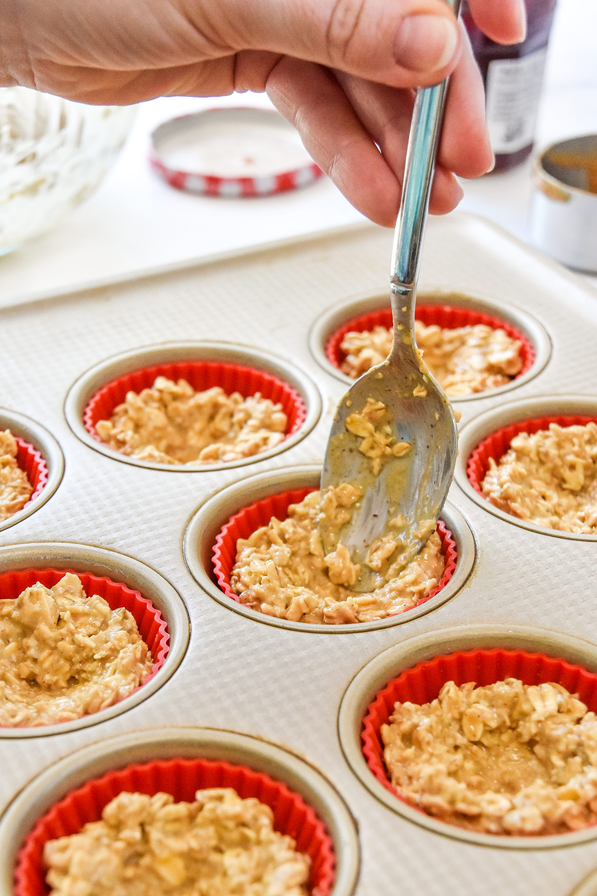 using a spoon to press oatmeal up the sides of the muffin tin.