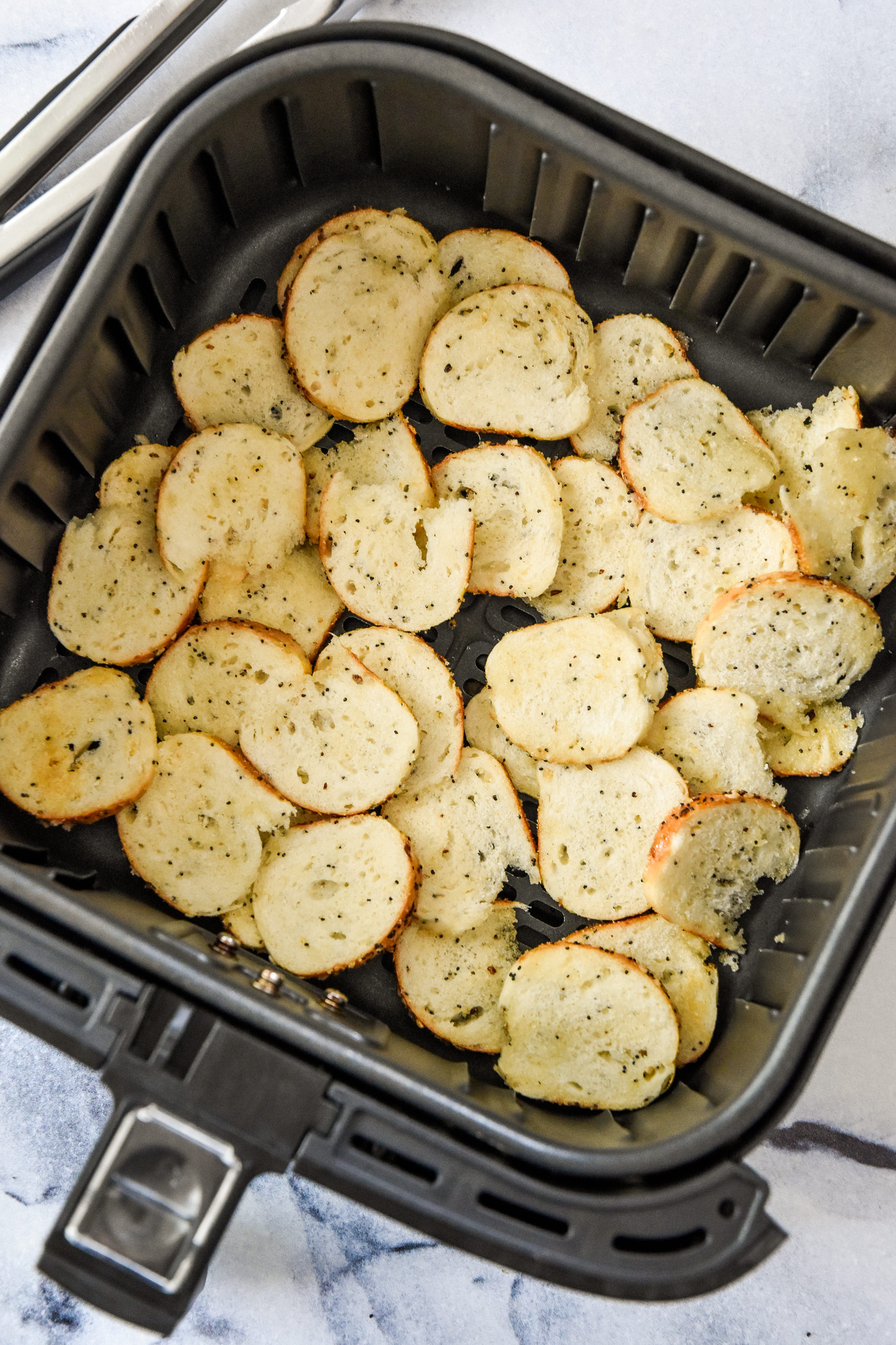 uncooked bagel chips in the air fryer basket ready to be cooked.