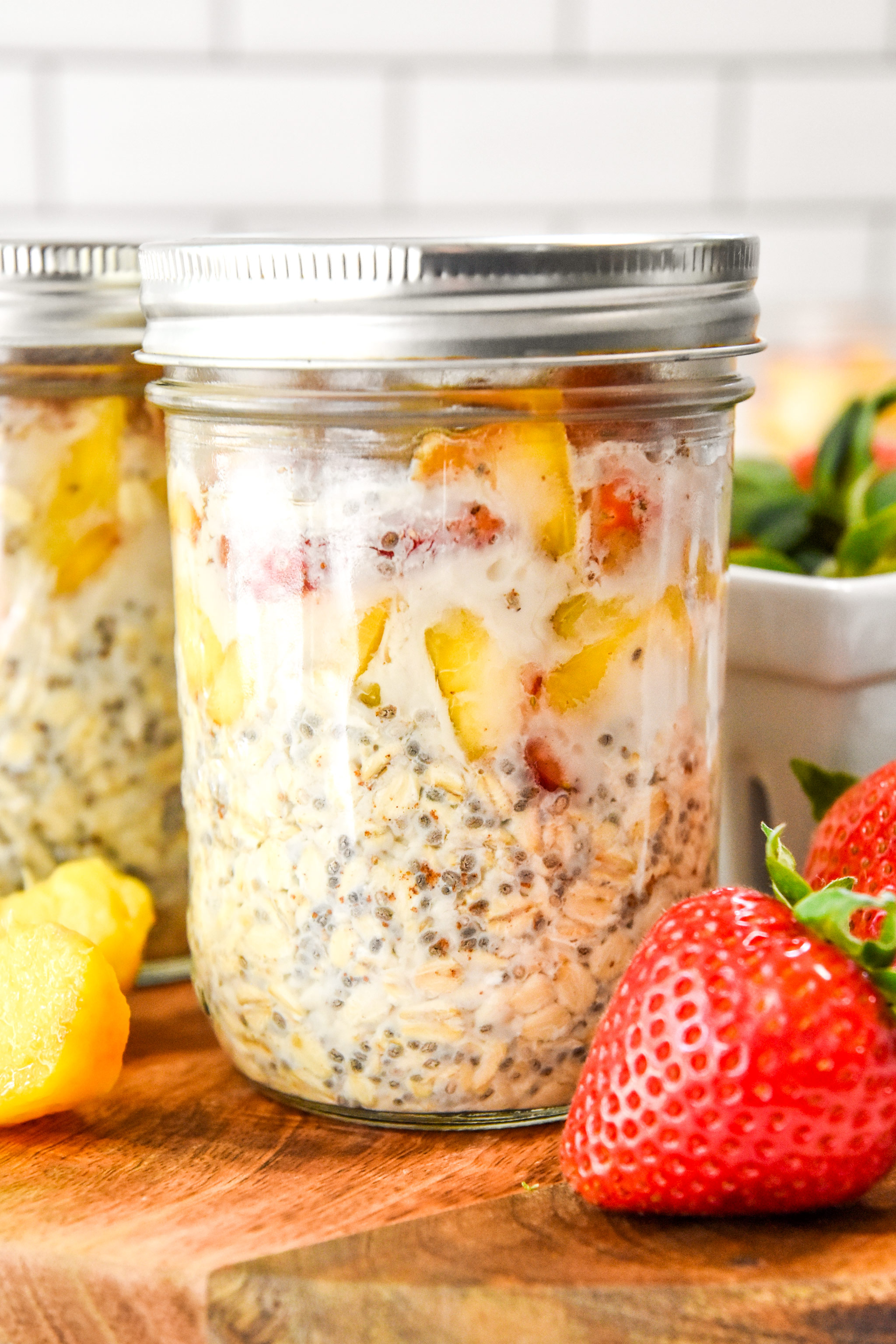 jar of strawberry peach overnight oats on a cutting board with fresh fruit.