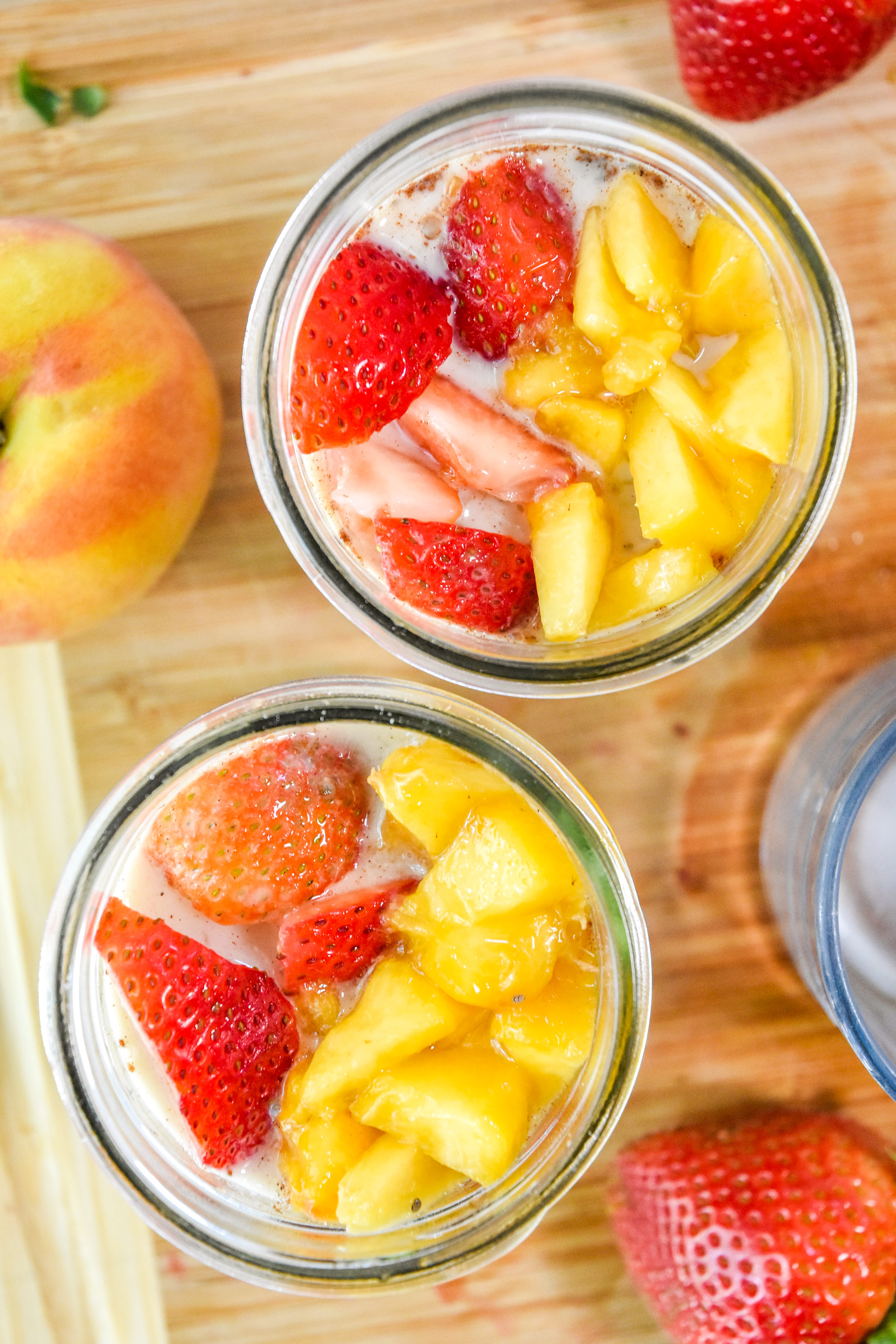 tops of the mason jars of strawberry peach overnight oats with lots of fresh fruit.