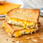 air fryer tuna melt cut in half stacked on a cutting board.