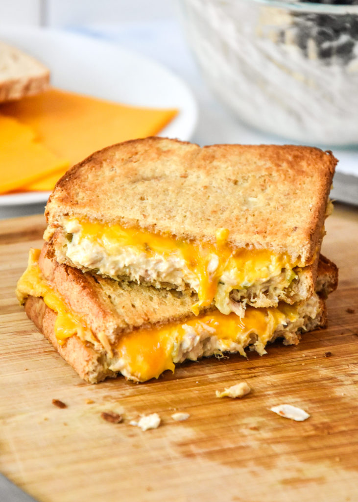 air fryer tuna melt cut in half stacked on a cutting board.