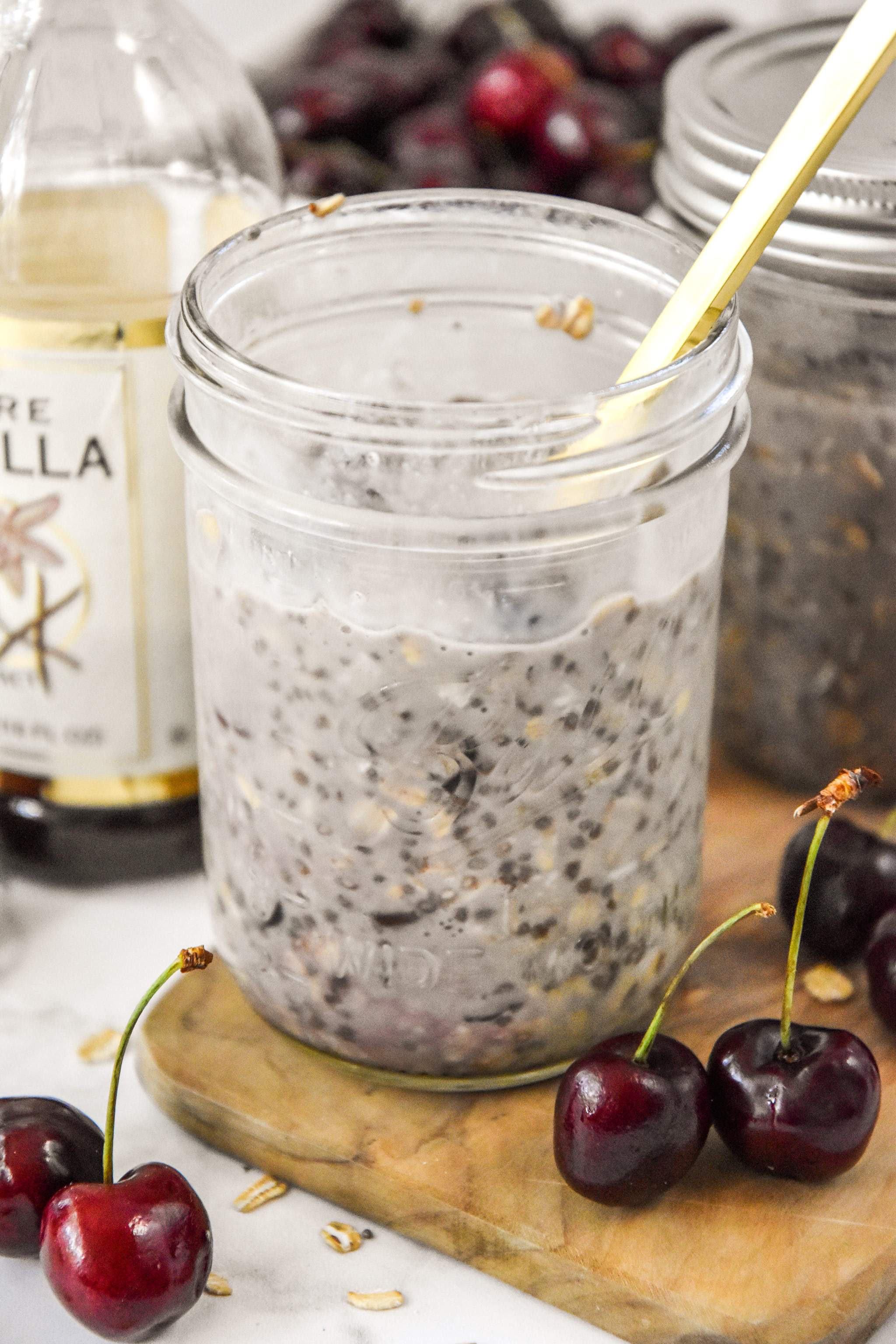 cherry vanilla overnight oats in a jar with a gold spoon.