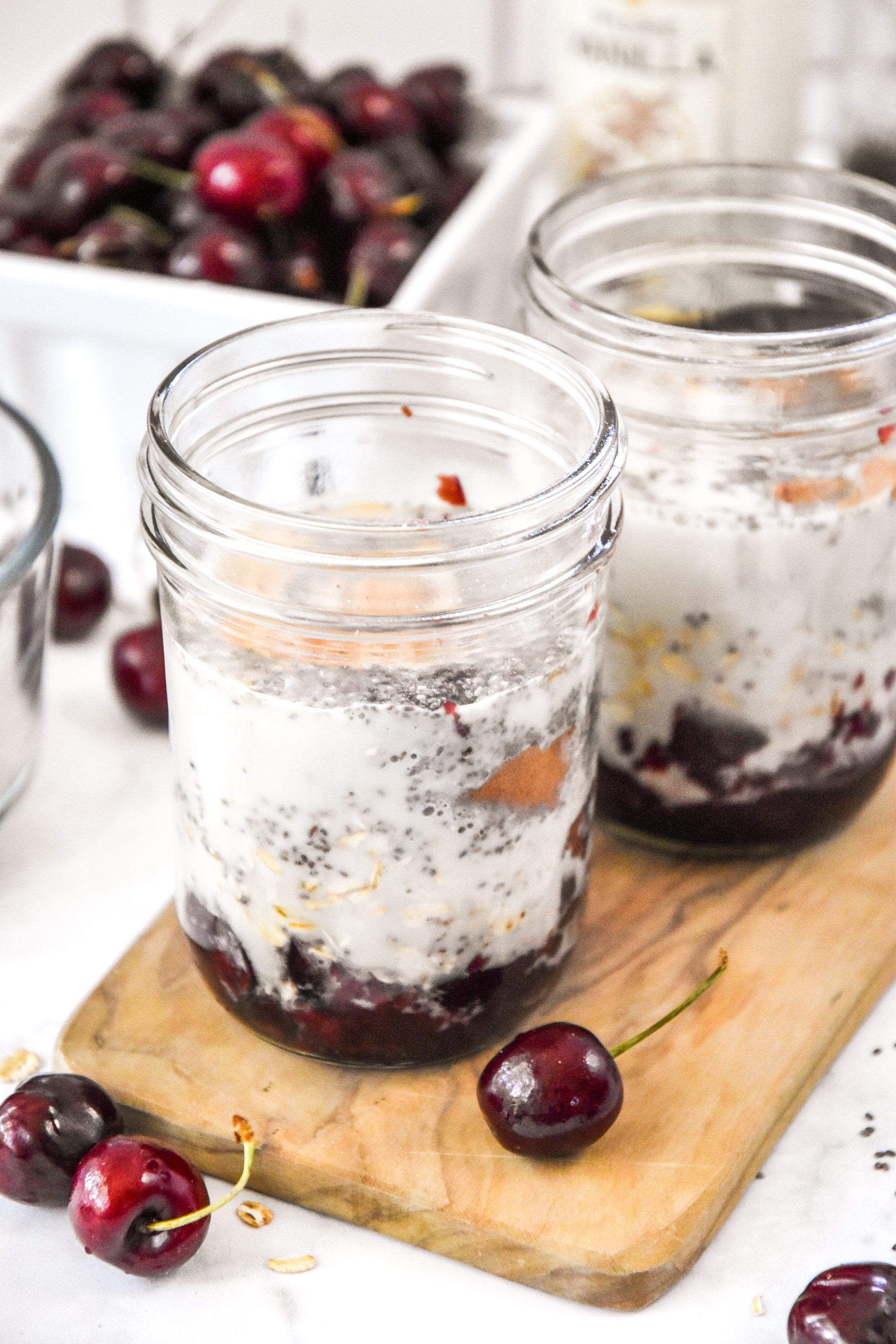 two jars of cherry vanilla overnight oats before being stirred up.