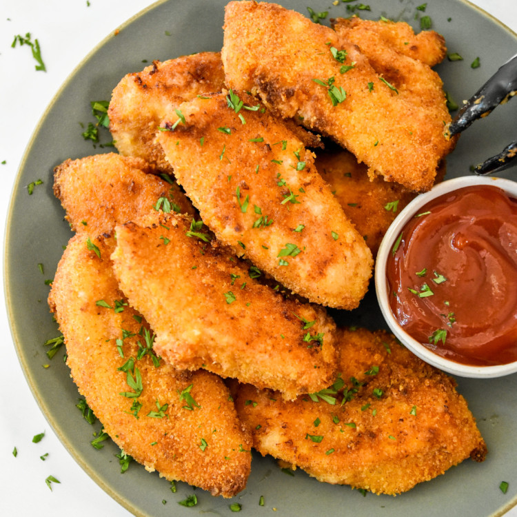 air fryer breaded chicken tenders on a plate with ketchup.