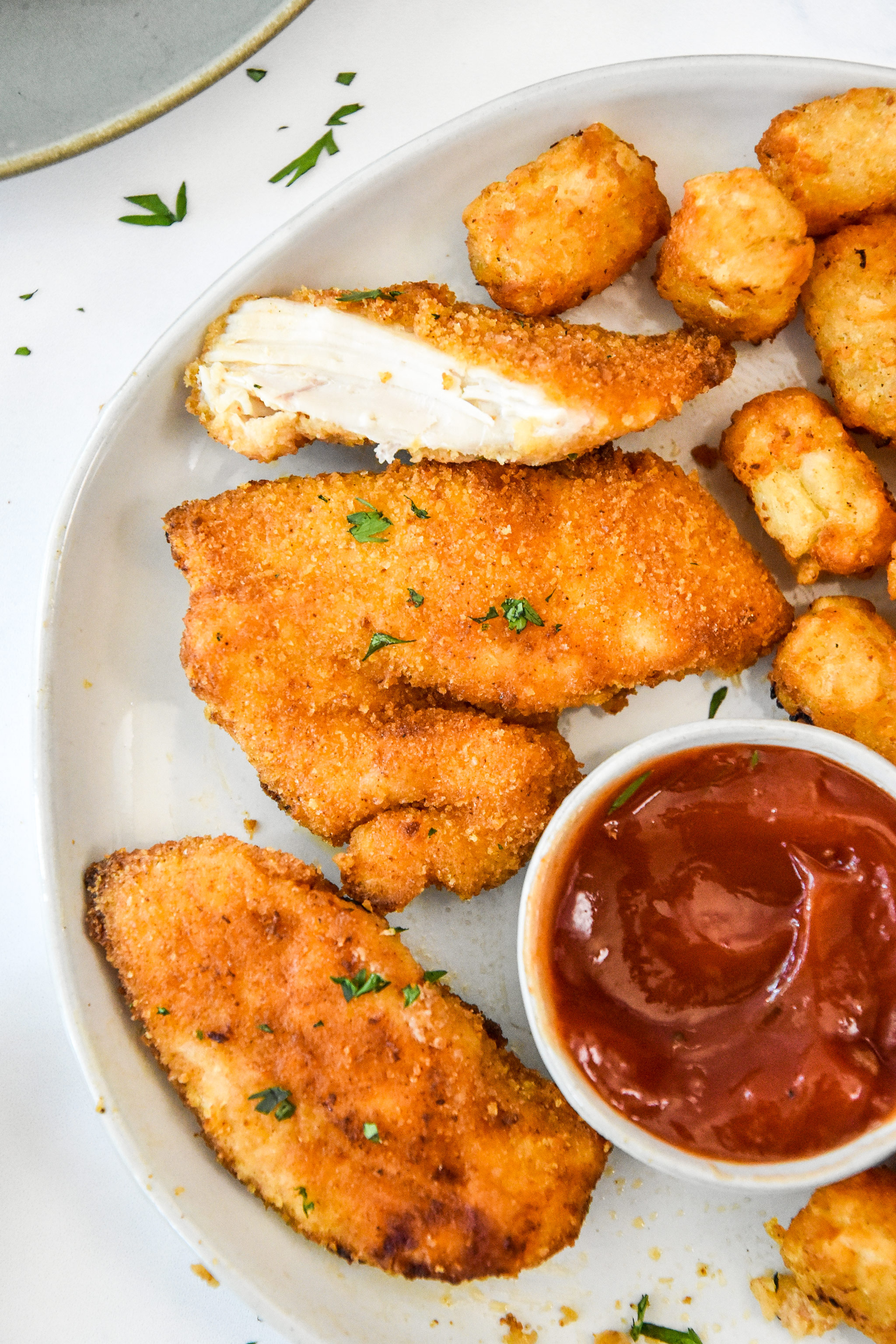 eating breaded chicken tenders with tater tots and ketchup.