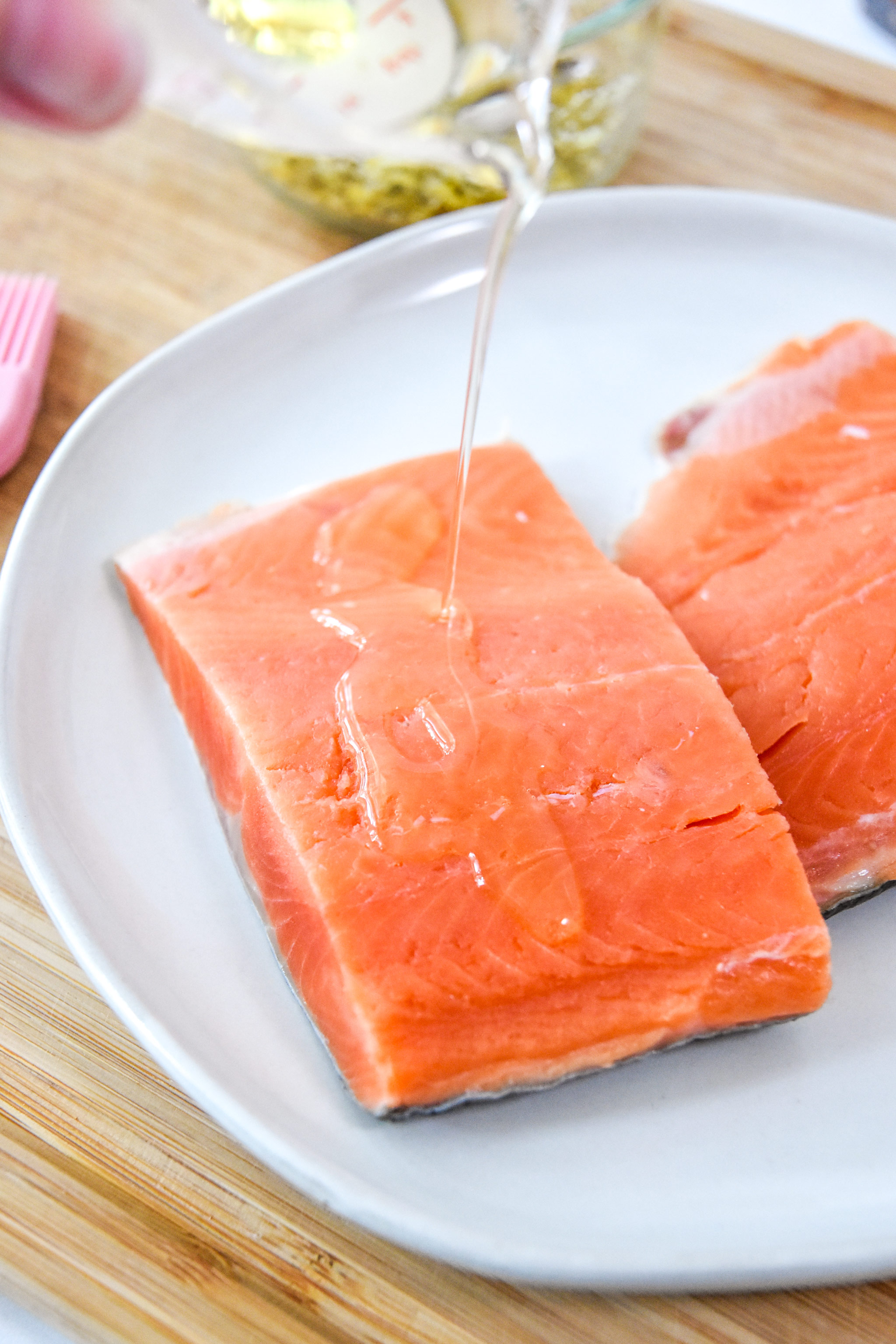 pouring oil on the salmon to coat both sides.