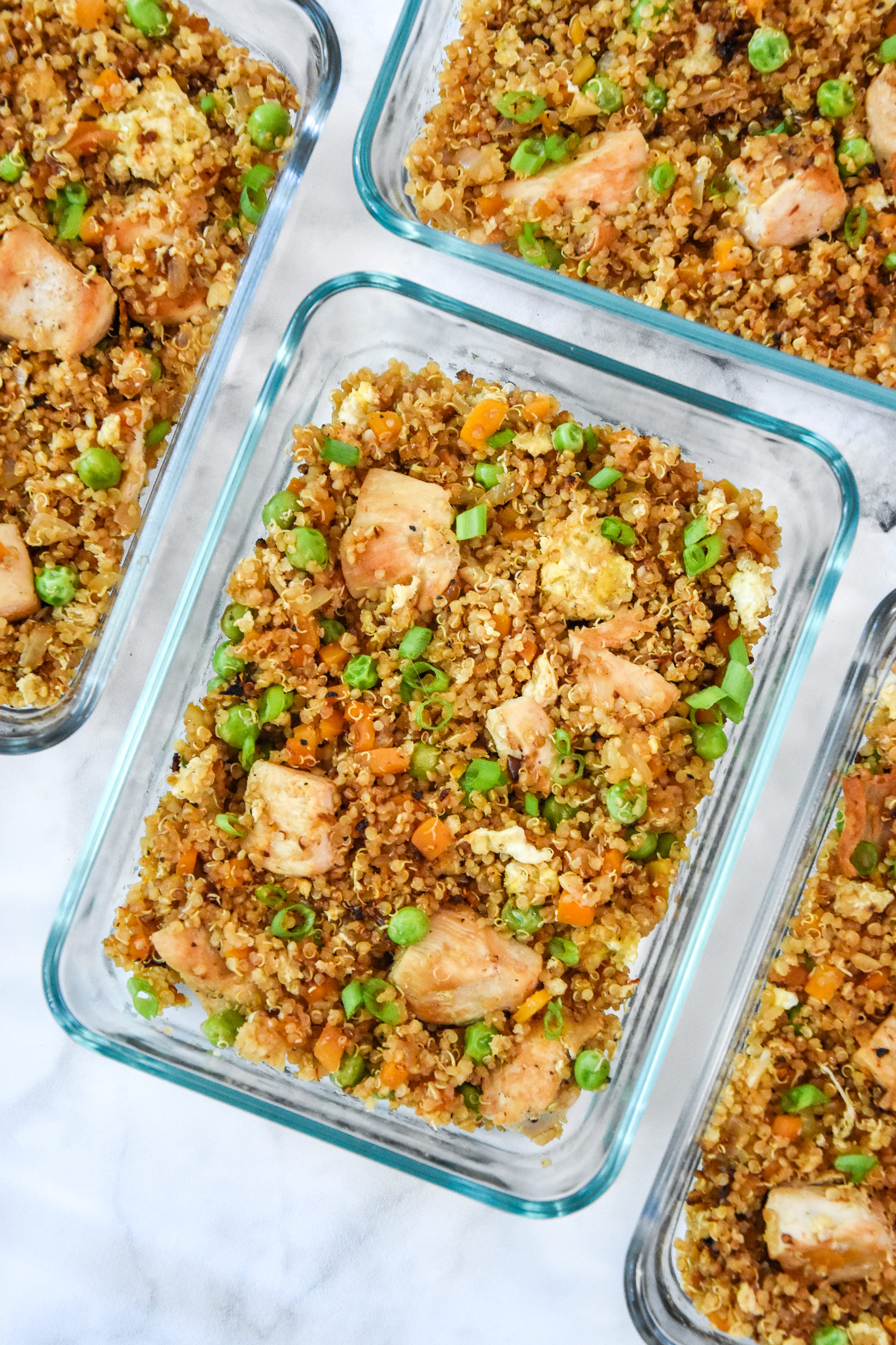 glass meal prep container with cooked chicken quinoa fried rice.