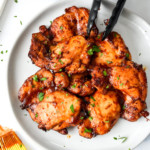 air fryer boneless bbq chicken thighs on a plate with tongs.