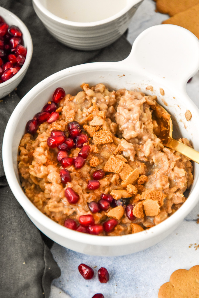 a bowl of instant pot gingerbread oatmeal with pomegranate seeds and ginger cookies on top.