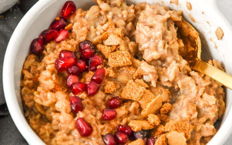 a bowl of instant pot gingerbread oatmeal with pomegranate seeds and ginger cookies on top.