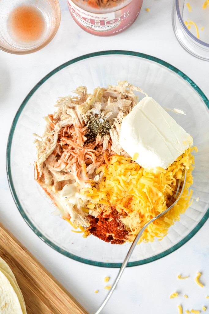 air fryer buffalo chicken flautas ingredients in a glass bowl before mixing up.
