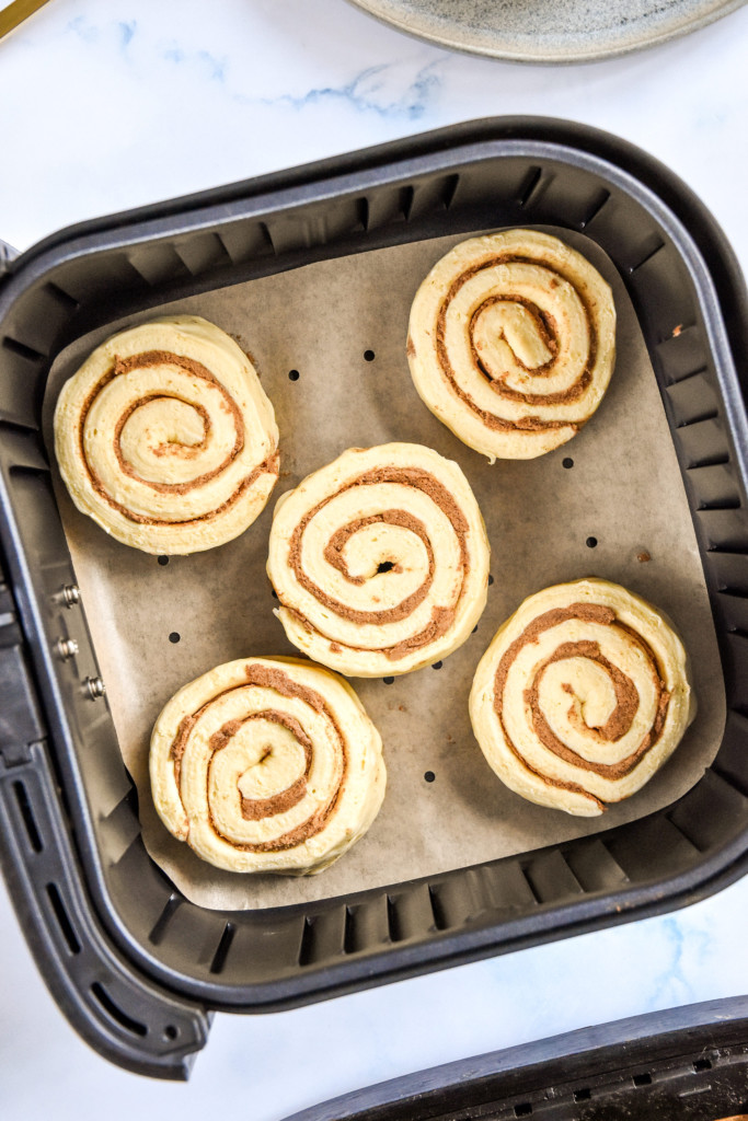 raw canned cinnamon roll dough in the air fryer basket.