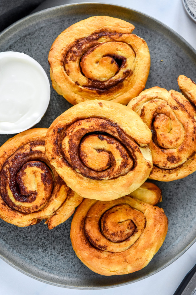 air fryer canned cinnamon rolls cooked on a plate before icing.
