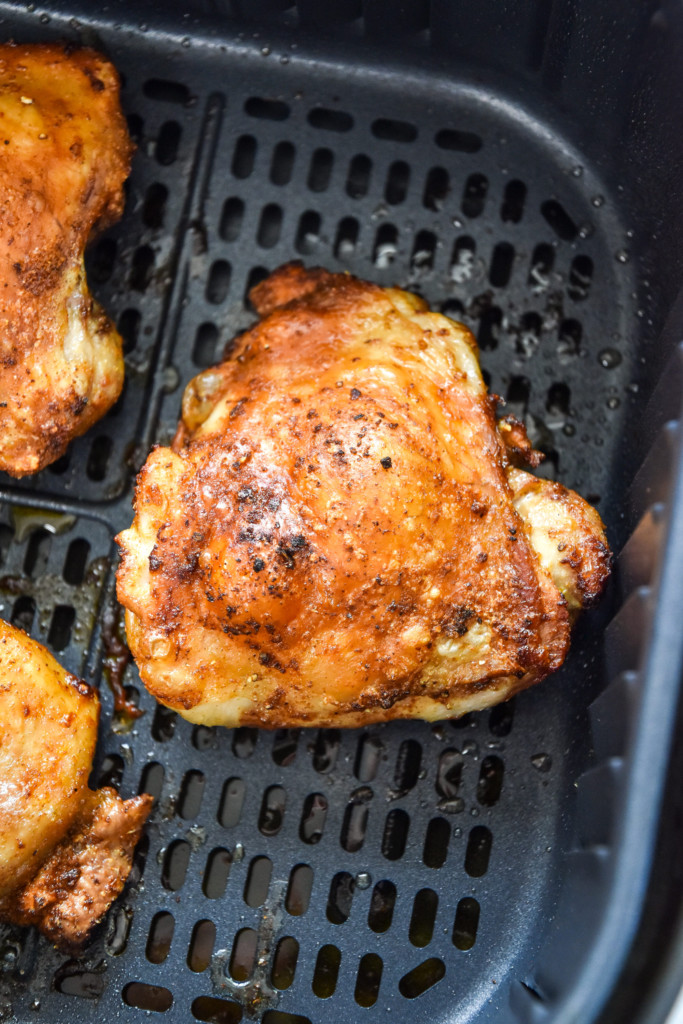 close up of cooked bone-in chicken thigh in the air fryer.