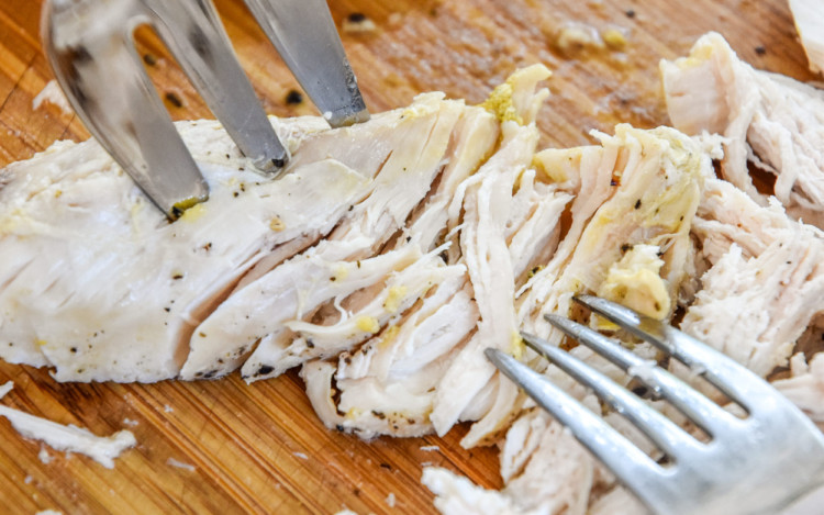 shredding chicken on a cutting board.