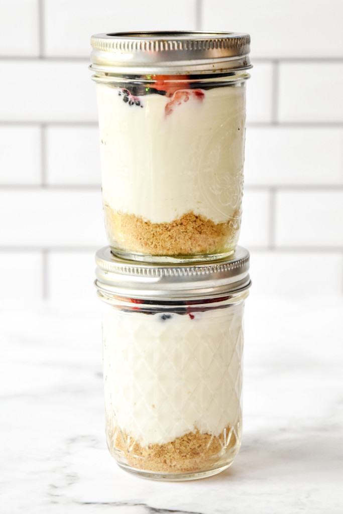 stacked meal prep jars of no-bake cheesecake greek yogurt cups.