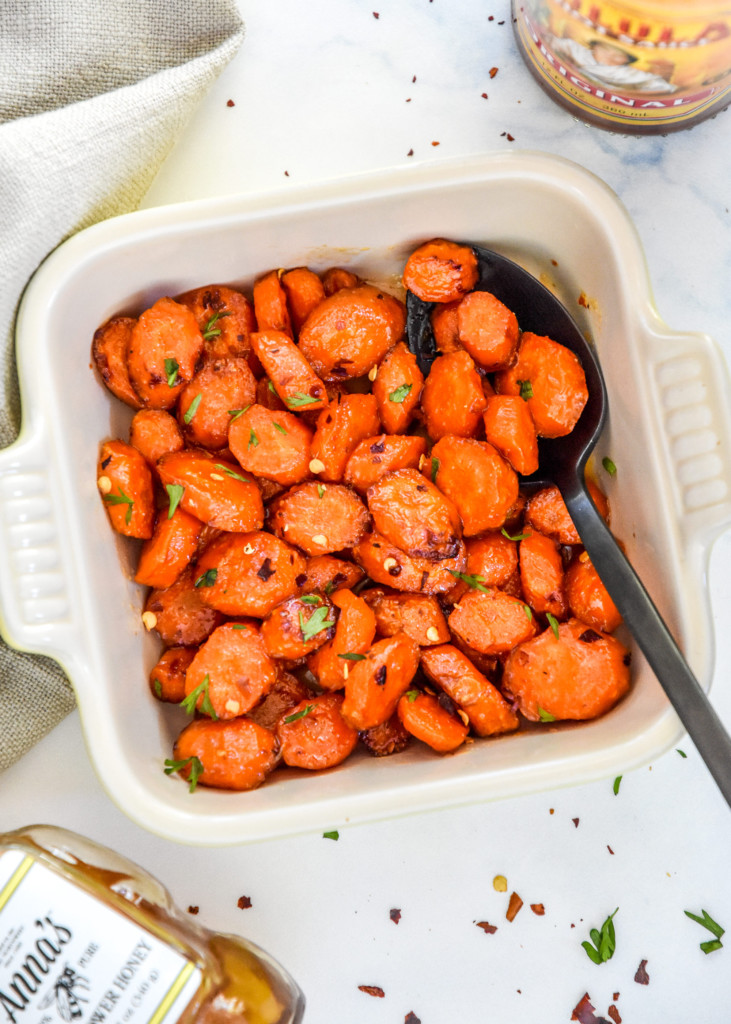 air fryer hot honey glazed carrots in a bowl with a black serving spoon.