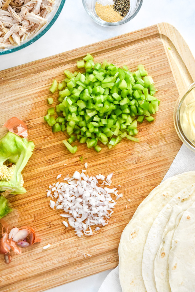 chopping green bell peppers and shallots for the caesar chicken salad.