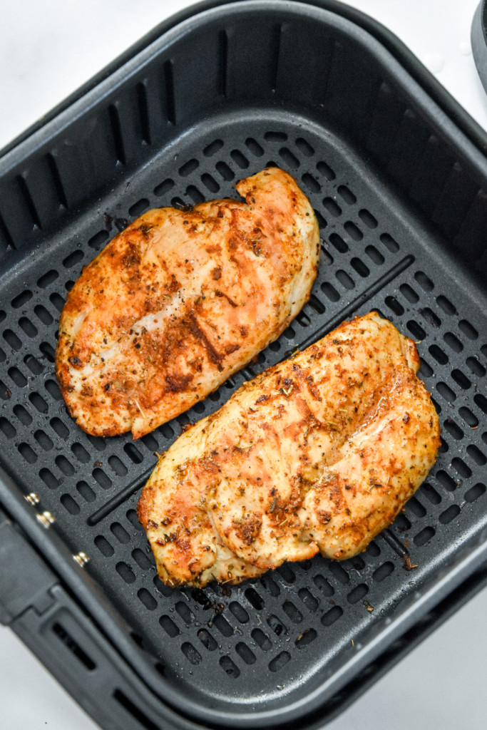 cooked juicy air fryer boneless chicken breasts in the air fryer basket.