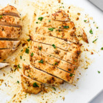 juicy air fryer chicken breasts cut into slices on a cutting board.