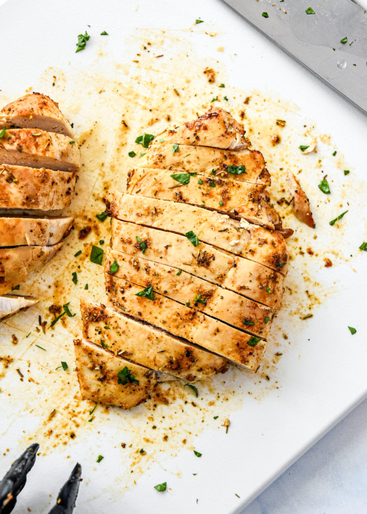 juicy air fryer chicken breasts cut into slices on a cutting board.
