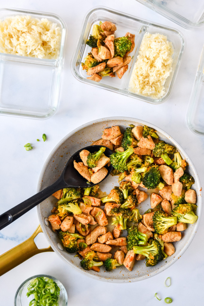 portioning the buffalo chicken and broccoli meal prep in the glass containers.
