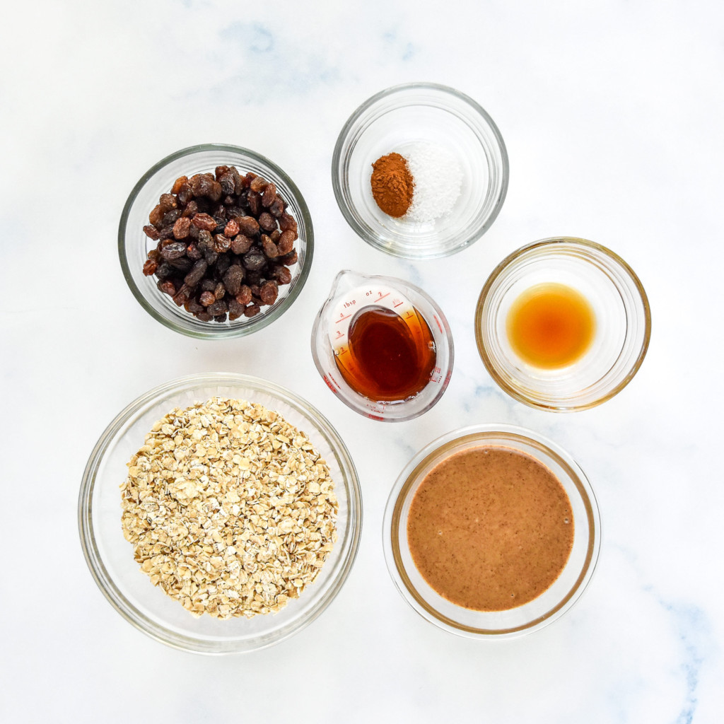 ingredients in glass bowls on the counter to make the no-bake oatmeal raisin cookie balls.