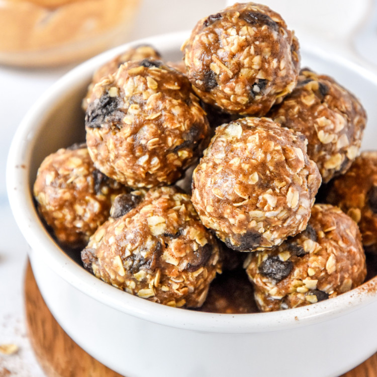 no-bake oatmeal raisin cookie balls stacked in a white bowl.