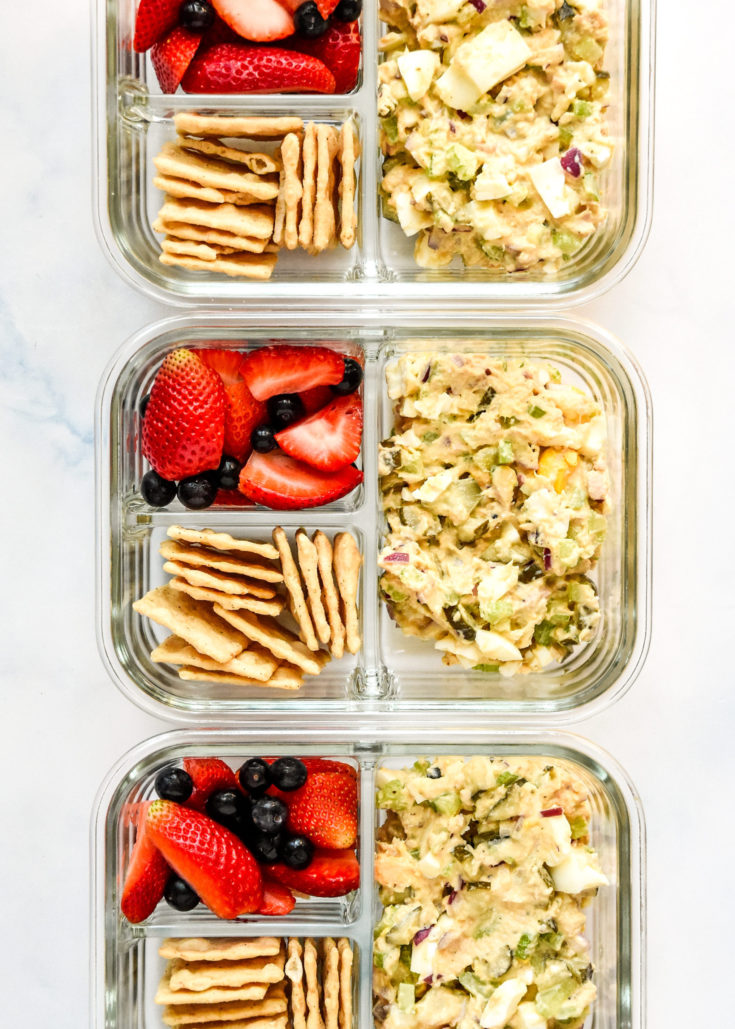 tuna egg salad meal prep with berries and crackers in glass meal prep containers.