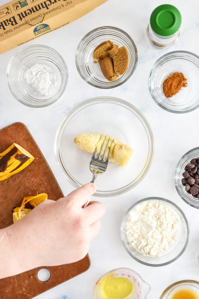 mashing the banana in a glass bowl to make the air fryer cookie.