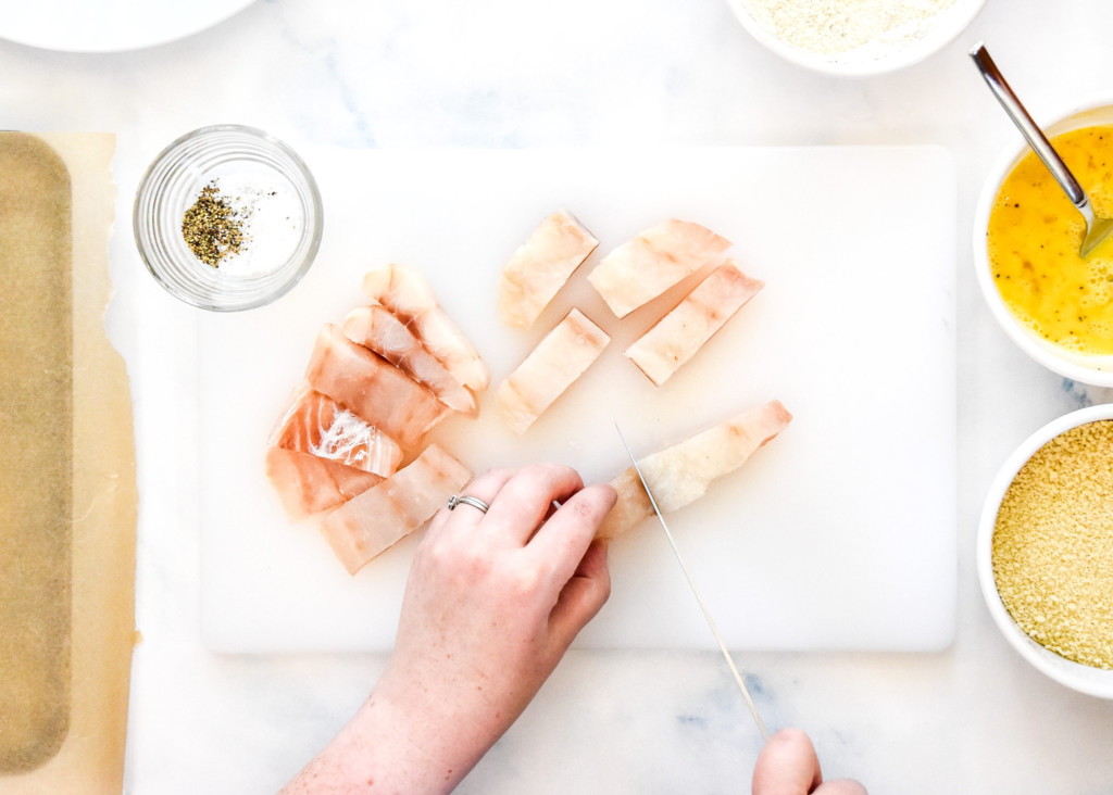 cutting a large piece of cod into small sticks one inch thick.